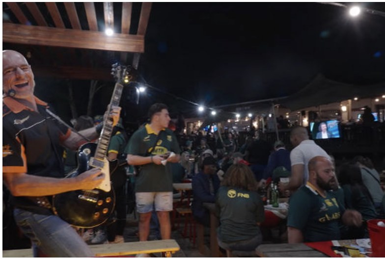 Live guitarist performing for fans at an outdoor rugby fan zone